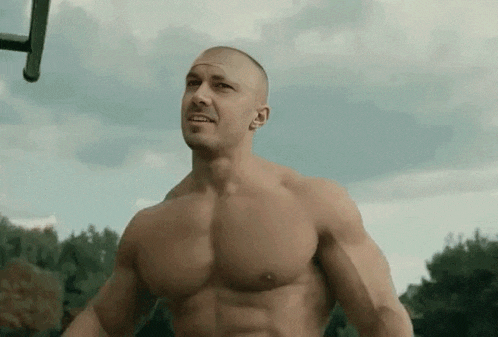 a shirtless man is standing in front of a basketball hoop in a park .