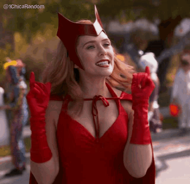 a woman in a red dress and red gloves is making a peace sign .