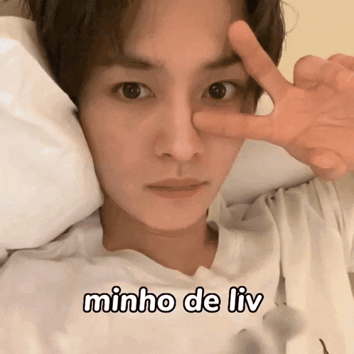 a young man is making a peace sign with his fingers and the words minho de liv are below him