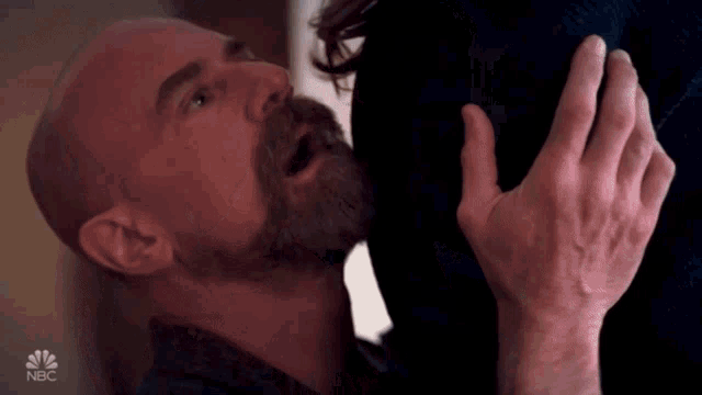 a bald man with a beard is kissing a woman 's butt on nbc television