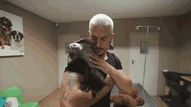 a man with a tattoo on his arm is holding a small dog