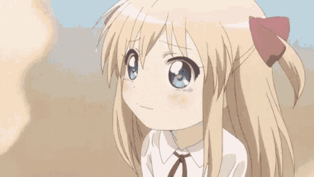 a little girl with long blonde hair and blue eyes is smiling and looking at the camera .