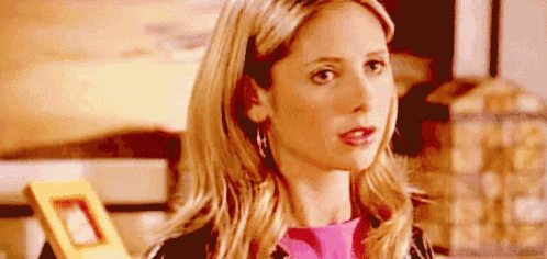 a close up of a woman 's face with a pink shirt and earrings .