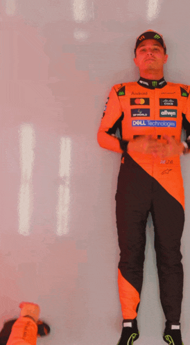 a man in an orange and black racing suit with dell technology written on his pants