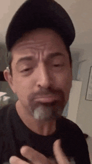 a man with a beard wearing a hat is making a funny face .