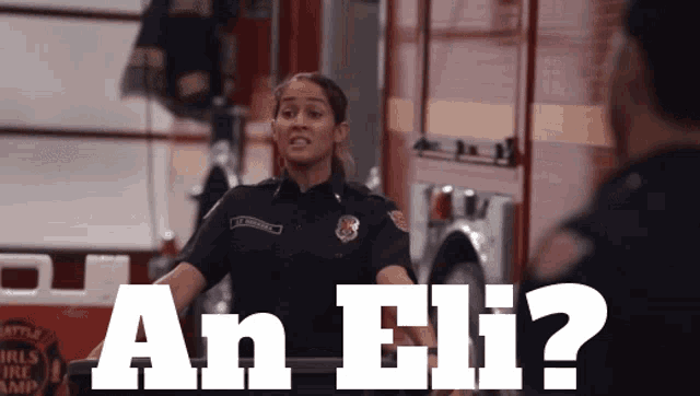 a female firefighter is standing in front of a fire truck and says " an eli "