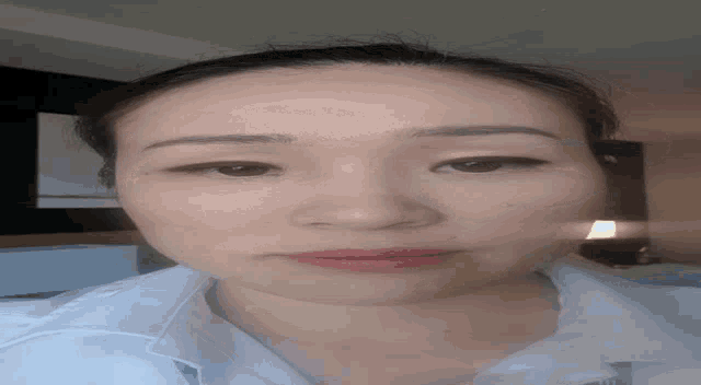 a close up of a woman 's face with brown eyes and a white shirt