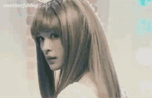 a woman with long hair and bangs is wearing a white dress and a wig .