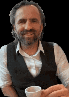 a man with a beard is smiling and holding a cup