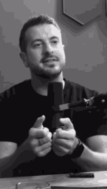 a man in a black shirt is talking into a microphone in a black and white photo