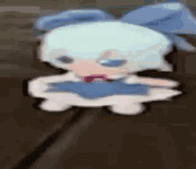 a cartoon character with a blue bow is sitting on a wooden table .
