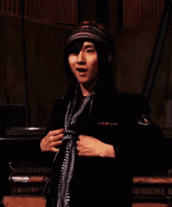 a man wearing a scarf and a hat is standing in a dark room .