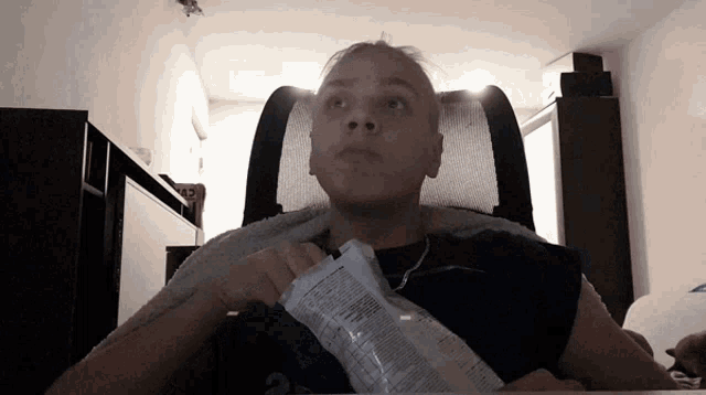 a man sitting in a chair holding a bag of chips with the number 2 on it