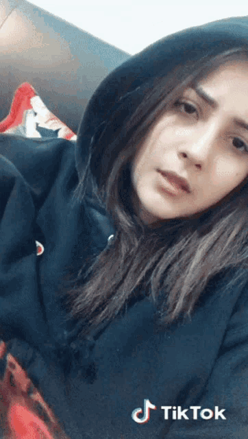 a woman wearing a black hoodie has a tiktok logo on the bottom