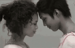 a man and a woman are touching their foreheads and smiling .