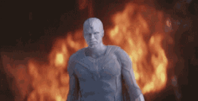 a statue of a man is standing in front of a large fire