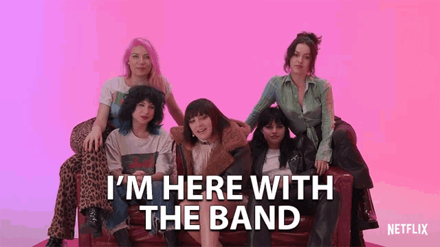 a group of women sitting on a red couch with the words i 'm here with the band