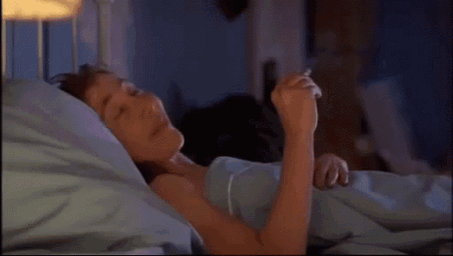 a woman is laying in a bed without a shirt on and making a funny face .