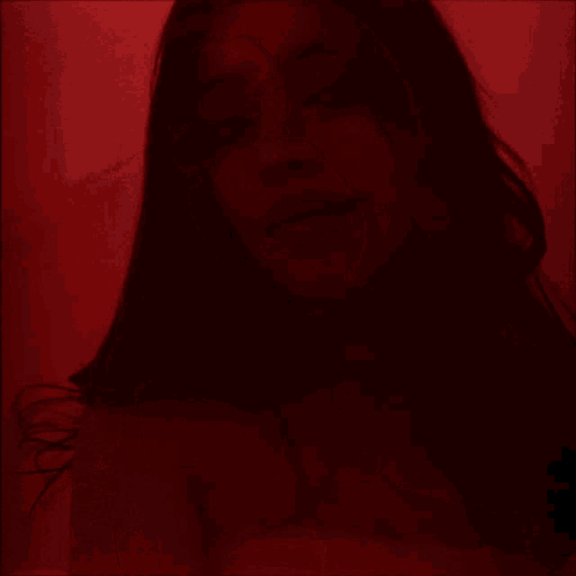 a woman with long dark hair is standing in a red room