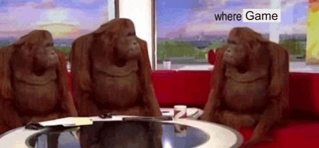 three orangutans are sitting at a table in front of a window in a room .