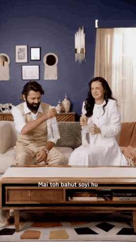 a man and a woman are sitting on a couch in a living room with mai toh bahut soyi hu written in the corner
