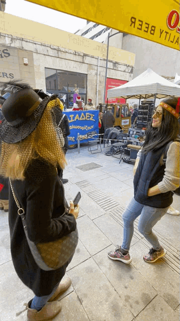two women standing in front of a yellow sign that says ' iadex '