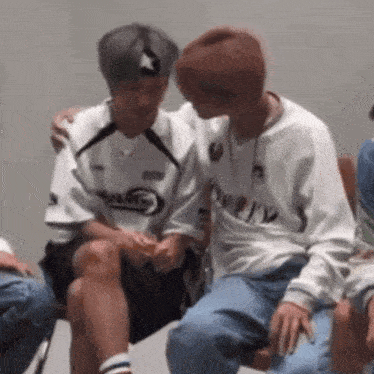 a couple of men are sitting next to each other on a chair .