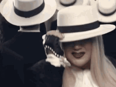 a woman wearing a white hat and sunglasses is standing in front of a group of people wearing white hats .