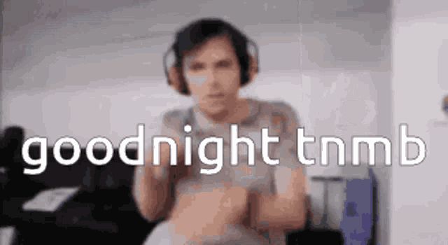 a man wearing headphones is saying goodnight tnmb in a blurry photo .