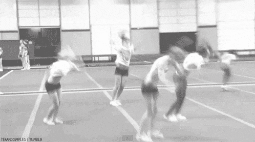 a group of cheerleaders are doing a trick on a track in a gym .