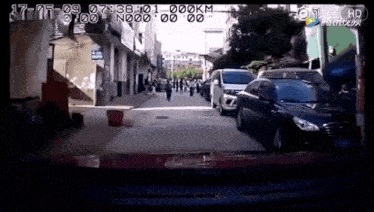 a car is driving down a busy street with a lot of cars parked on the side of the road .