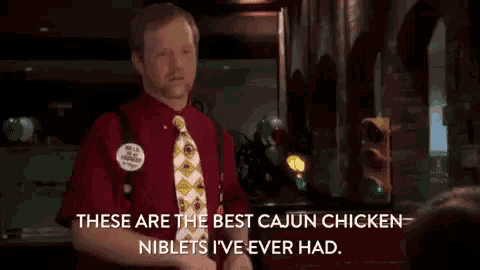 a man in a red shirt and tie is saying these are the best cajun chicken niblets i 've ever had