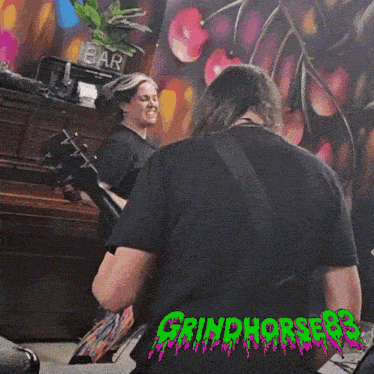 a woman singing into a microphone with the word grindhorses on the back of her shirt