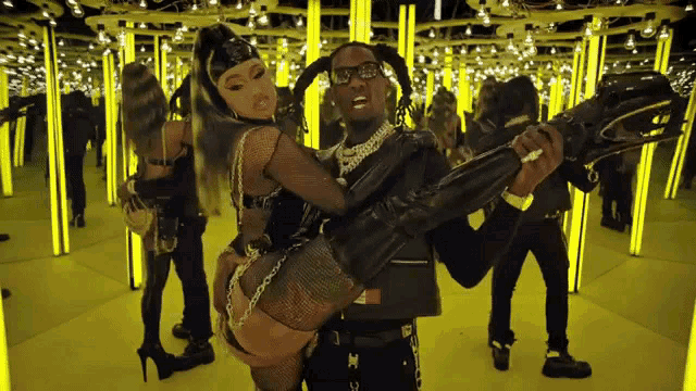 a man is holding a woman in his arms in front of a mirrored room filled with yellow lights .