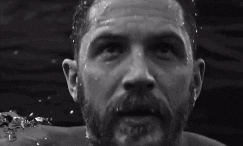a man with a beard is swimming in the water and looking at the camera .
