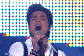 a man singing into a microphone with the number 16 on the bottom left