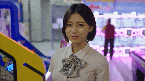 a girl in a school uniform is standing in front of a arcade machine that says ' arcade ' on it