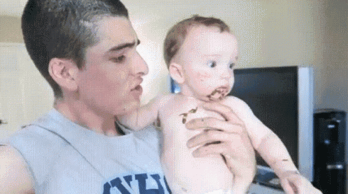 a man is holding a baby who is covered in chocolate