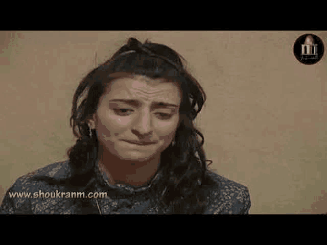 a woman is crying and making a funny face while sitting in front of a wall .