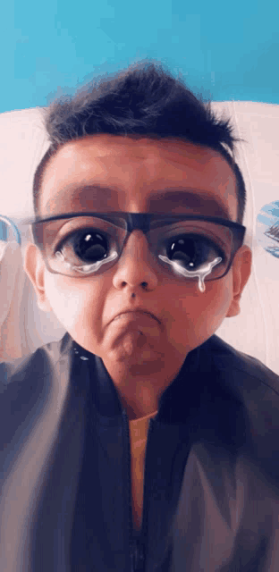 a young boy wearing glasses with tears running down his eyes