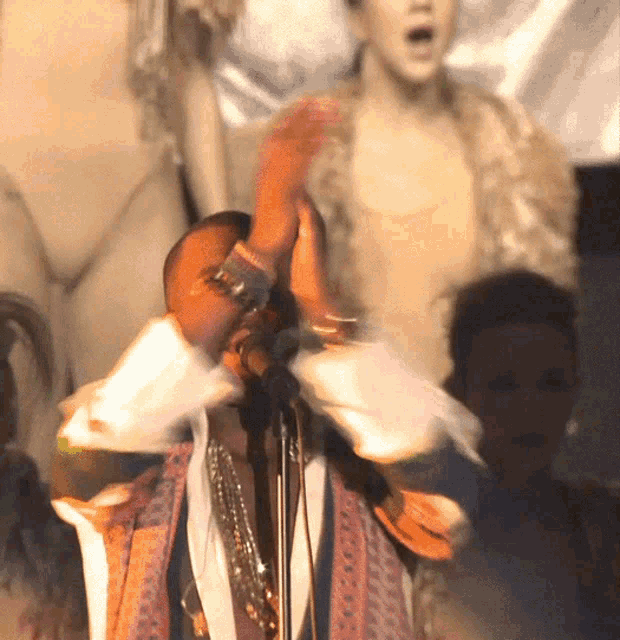 a man singing into a microphone in front of a naked woman