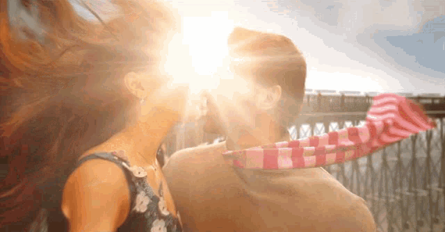 a man and a woman are kissing with the sun shining on their faces