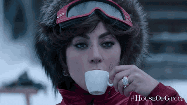 a woman is drinking from a white cup with #houseofgucci written on it