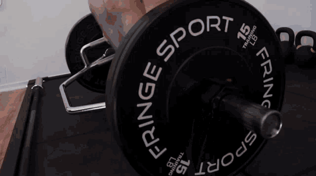 a person is lifting a barbell with fringe sport written on it