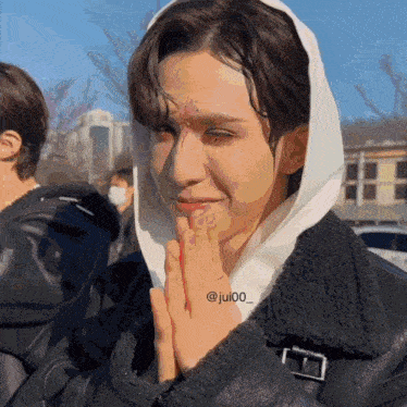 a man wearing a white hooded jacket has a tattoo on his face that says ' jesus '