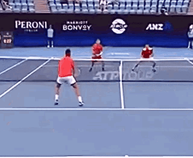 two tennis players are playing on a court with a peroni banner behind them