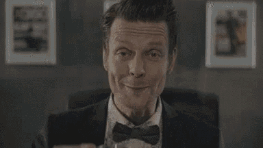 a man in a tuxedo and bow tie is drinking from a cup .