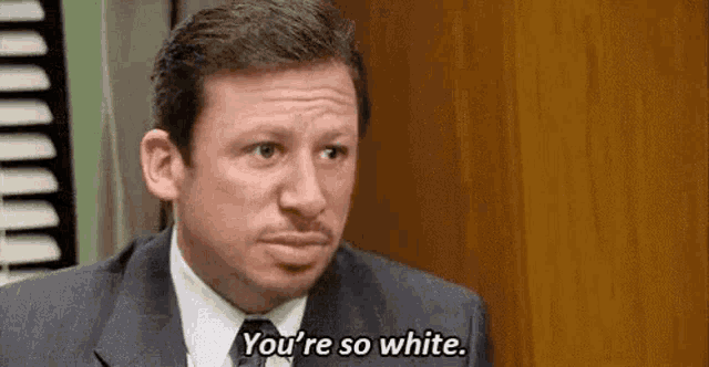 a man in a suit and tie is talking to another man in an office .