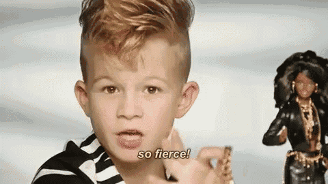 a young boy is standing next to a barbie doll and talking .
