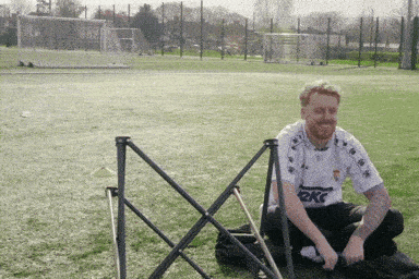 a man wearing a kappa shirt sits in the grass
